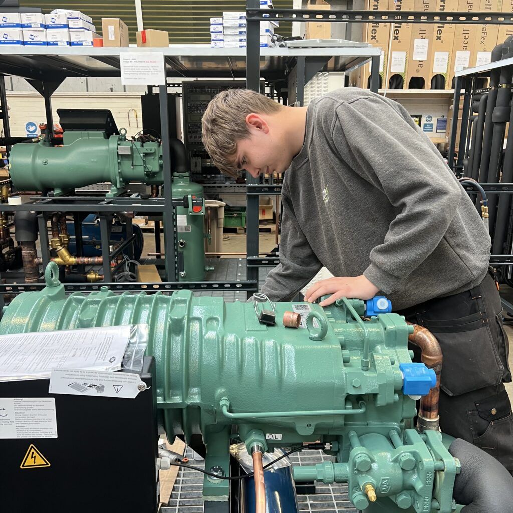 Apprentice engineer making adjustments to compressor before manufacture of blast freezer system commences